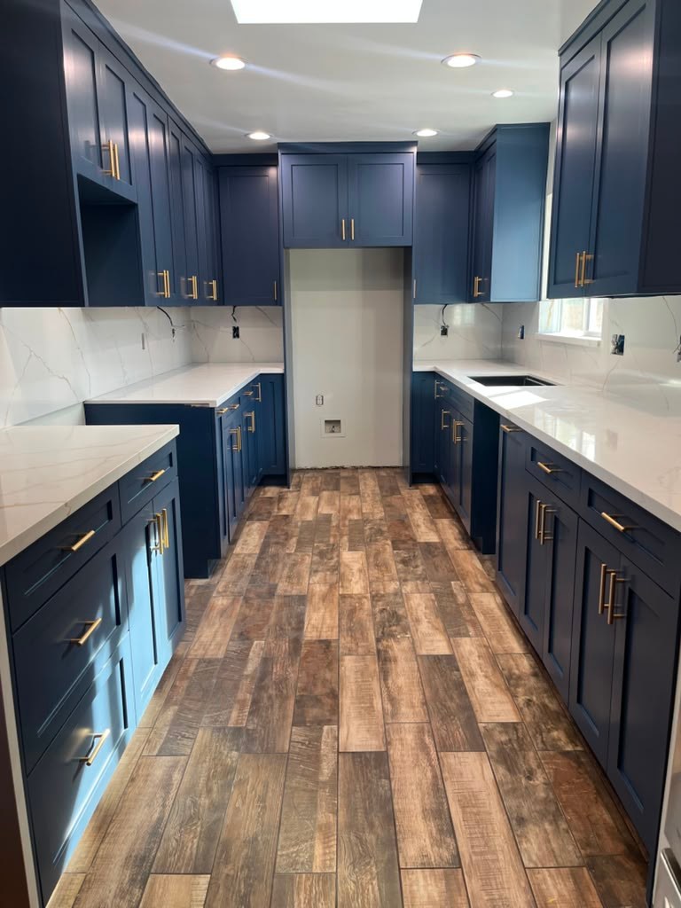Newly remodeled kitchen with navy-blue cabinets, white quartz countertops, and wood-look flooring