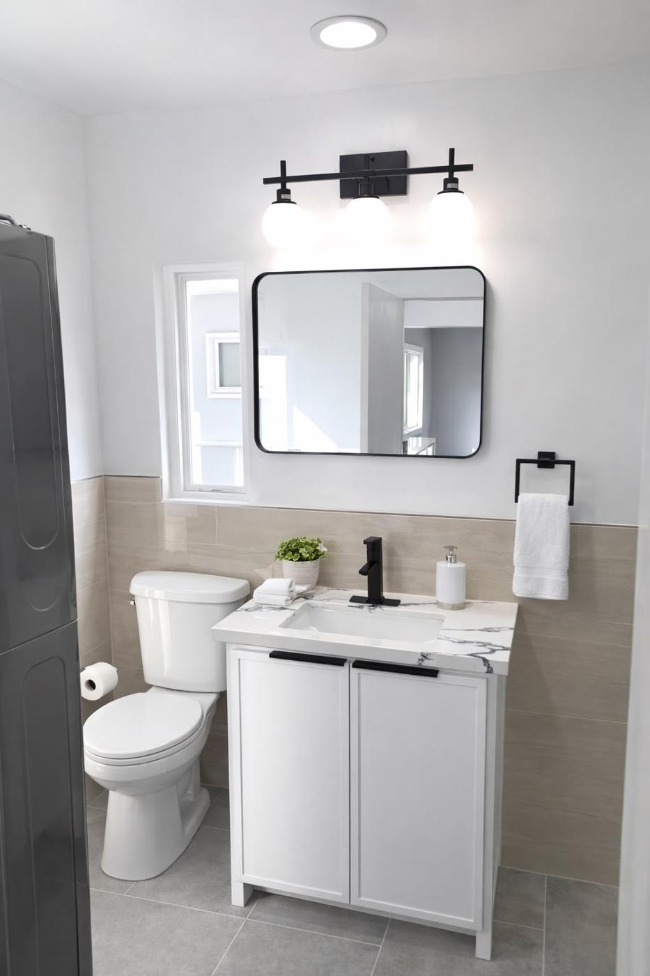 Remodeled bathroom with a white vanity, framed mirror, and toilet