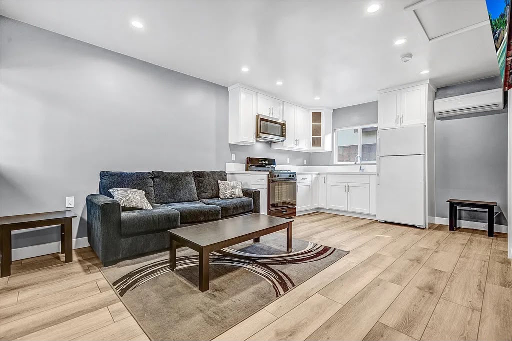 Spacious open-plan kitchen and living room with white cabinets and wood-look flooring
