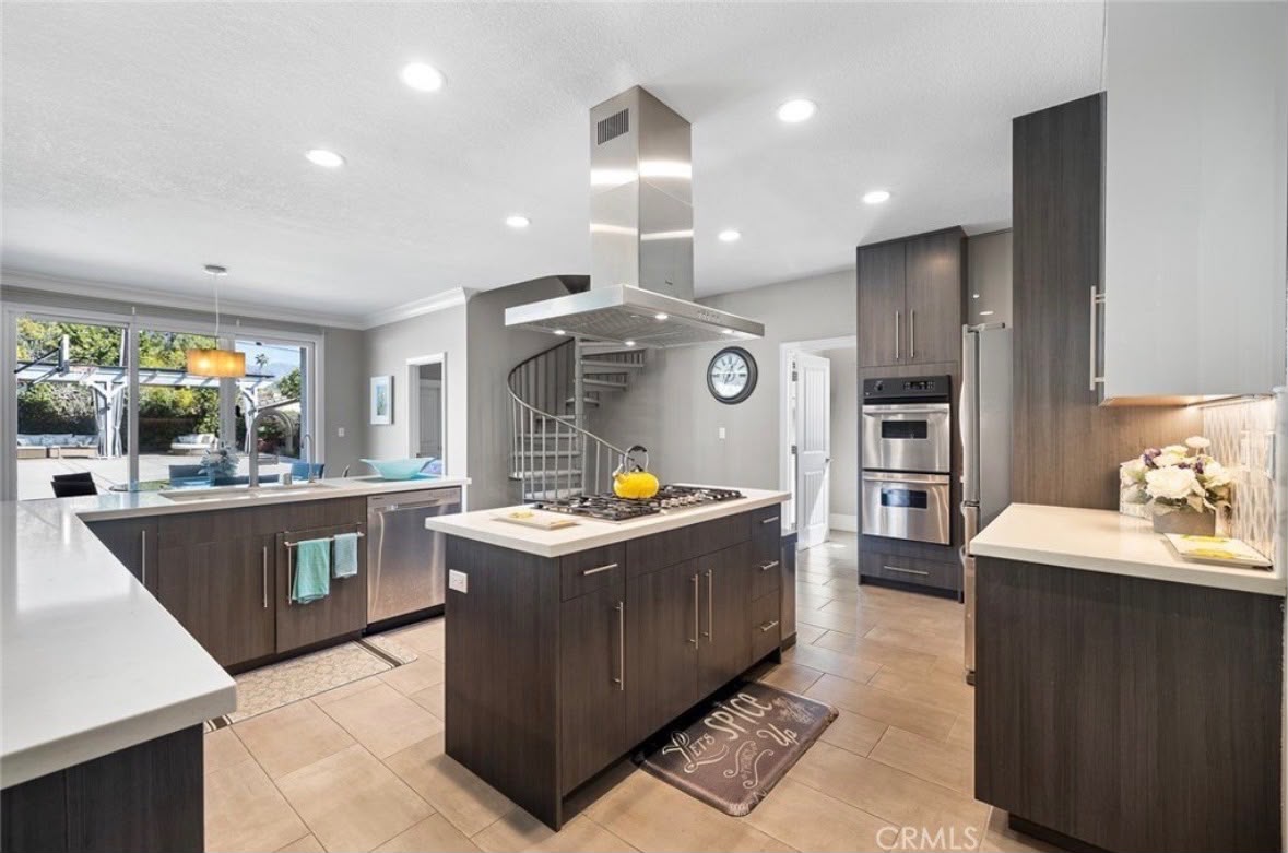 Remodeled kitchen with a central island, wood-look floors, and open sightlines to the living area