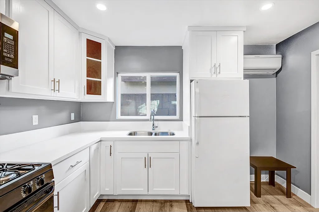 Completed kitchen remodel with white shaker cabinets, a black range, and wood-look flooring