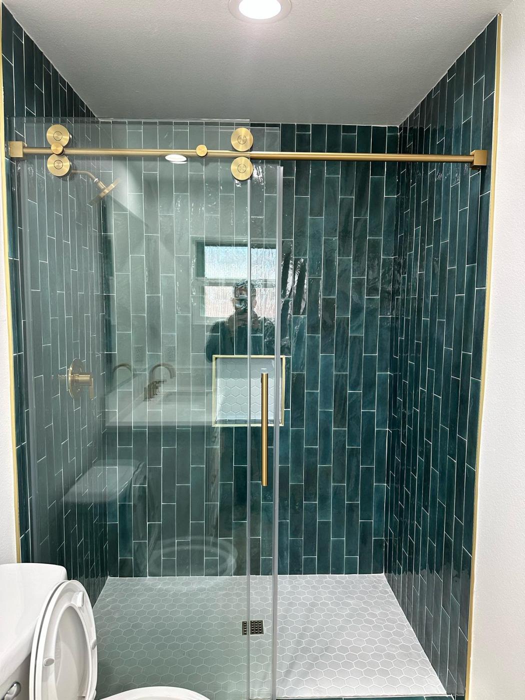 Modern bathroom with a frameless glass shower and dramatic green veined marble accent tile