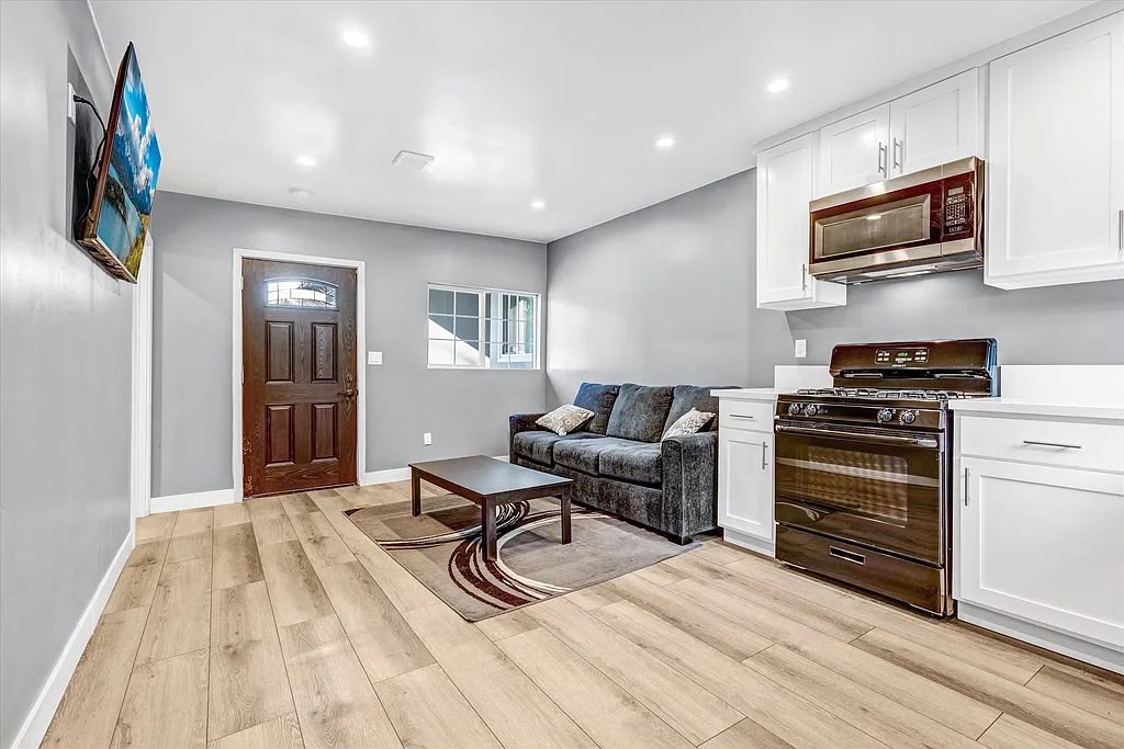 Open-concept kitchen and living space with a white island, wood-look floors, and abundant light