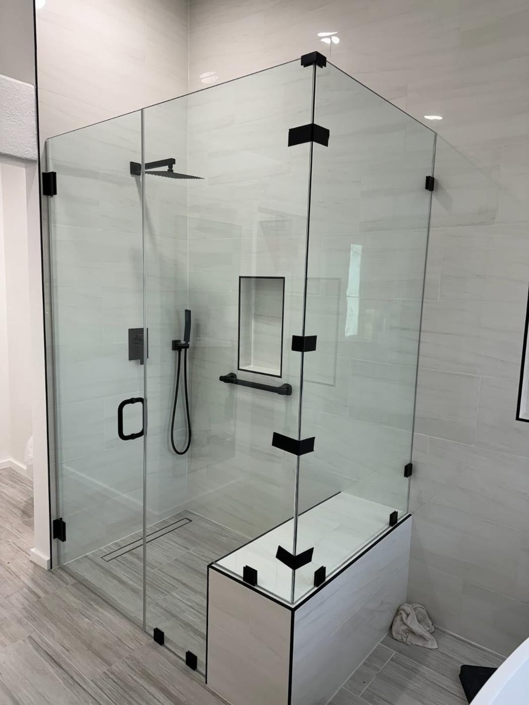 Completed bathroom remodel with a frameless glass walk-in shower, grey marble-look tile, and matte black fixtures