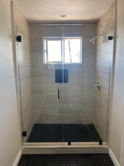 Remodeled bathroom with a tiled shower-tub combination, soft grey wall tile, and a frosted privacy window