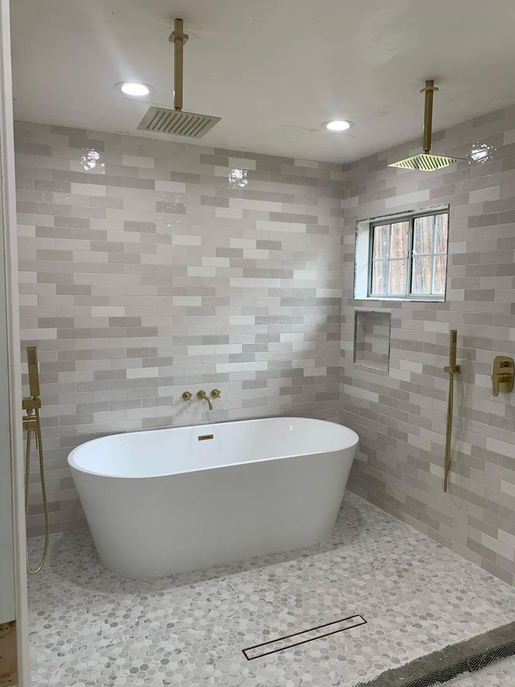 Luxury bathroom remodel with a freestanding soaking tub and a curved marble-look feature wall