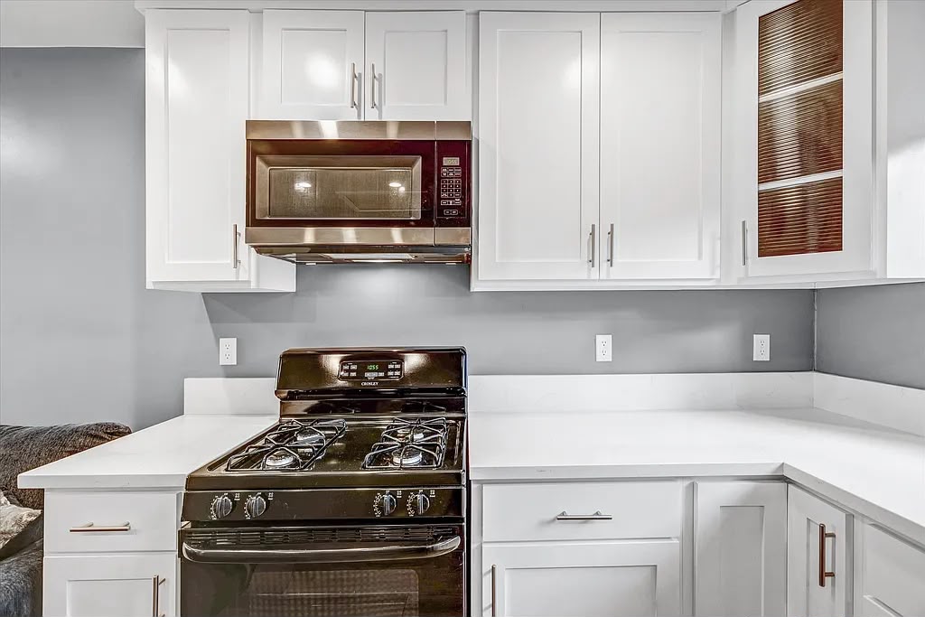Completed kitchen with white cabinets, dark countertops, and a black range